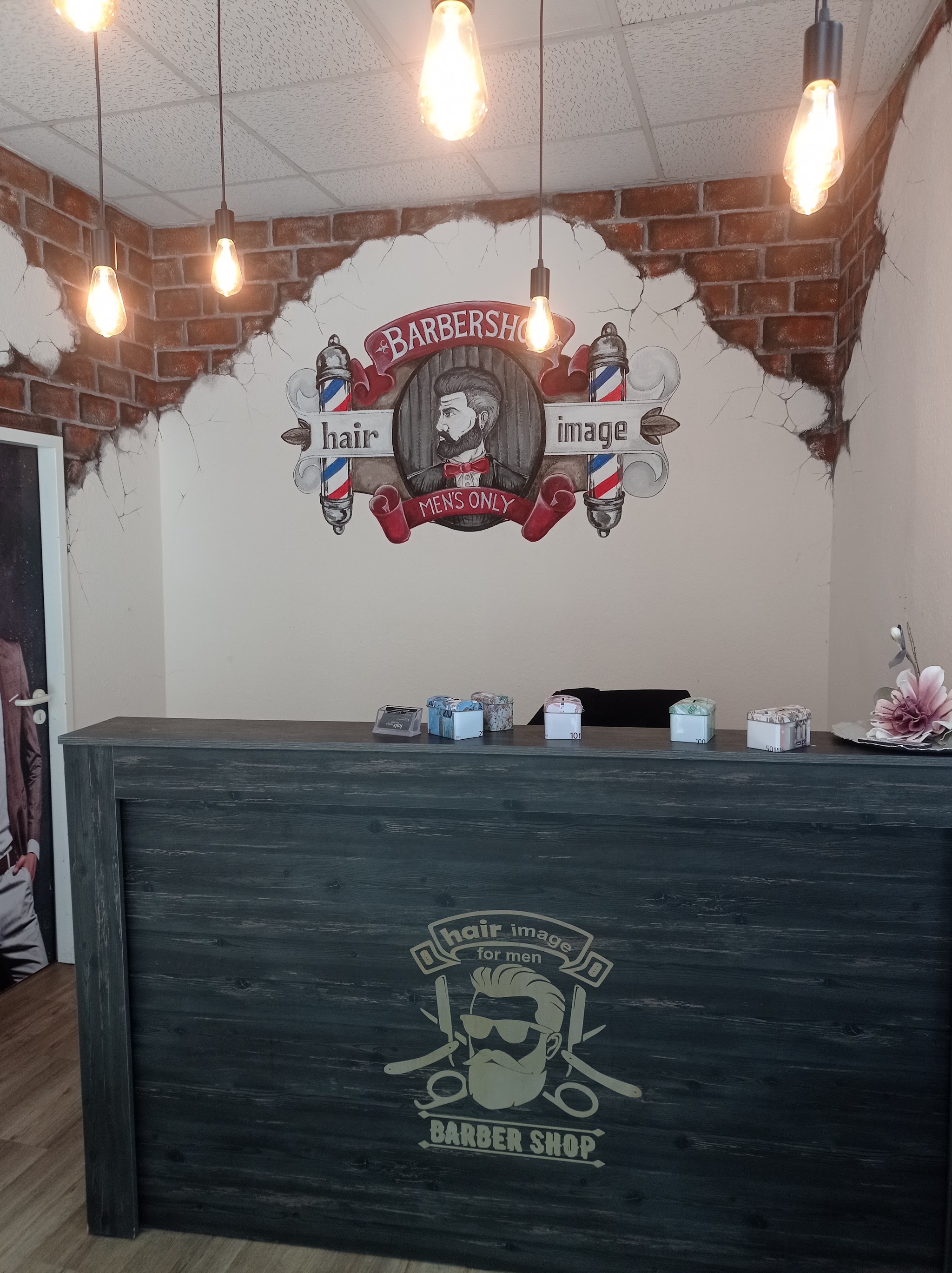 Empfangstresen mit handgemaltem Hair Image Barbershop Logo an der Ziegelwand